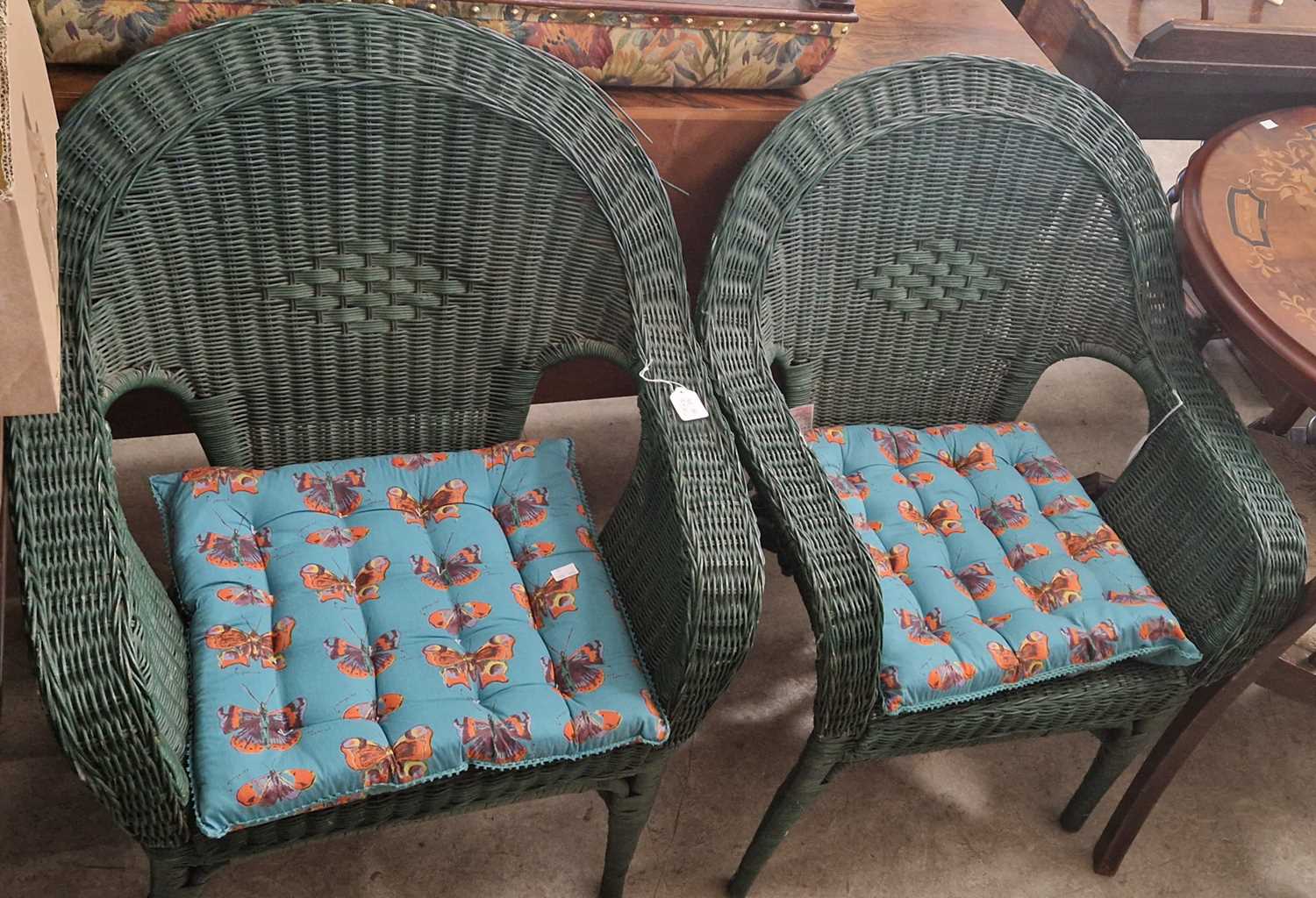 A pair of green-painted wicker conservatory / garden chairs.