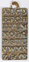 An antique brass alphabet plaque teaching aid, the reverse inscribed 'St. Pauls AD1729', cast in