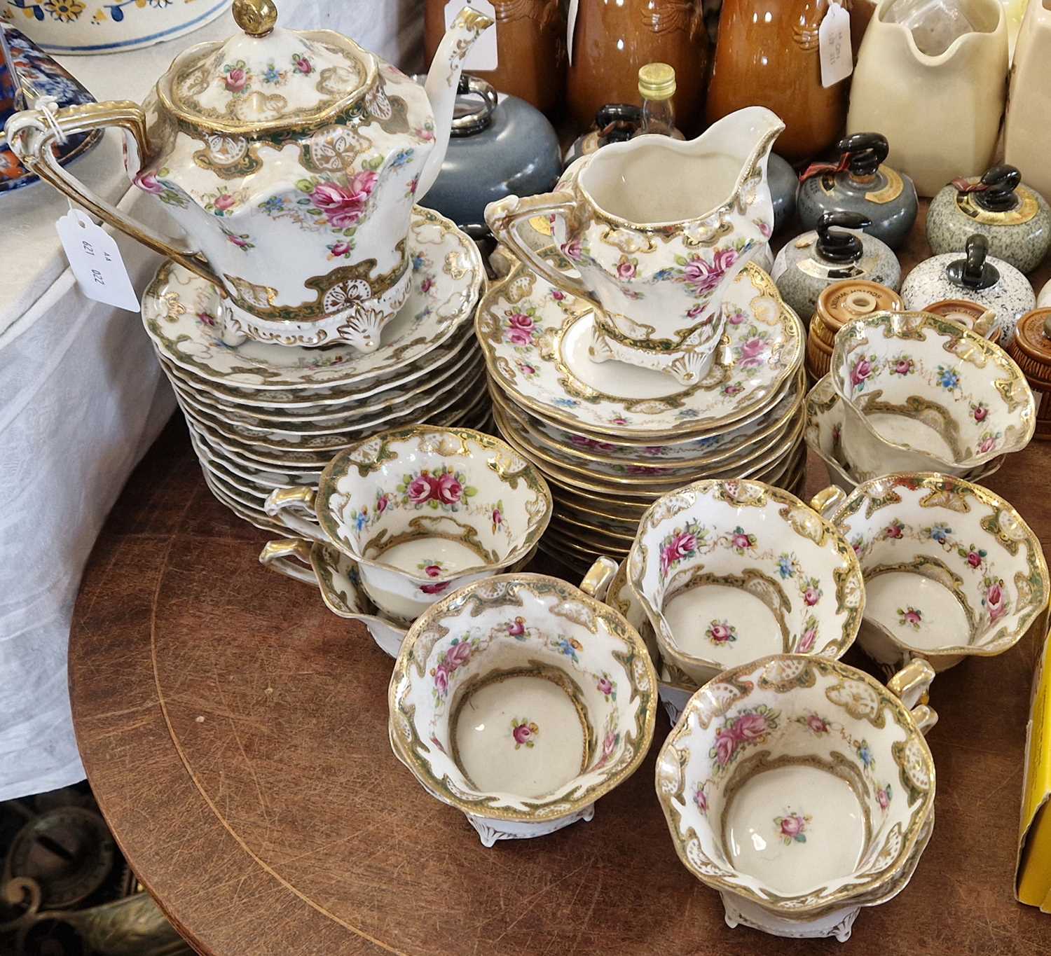 An antique porcelain hand-painted part tea set, with floral details and richly gilded borders, the