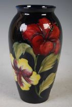 A Moorcroft pottery vase decorated with hibiscus on a dark blue ground, 18cm high.
