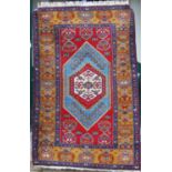 A Turkish rug, 20th century, the rectangular madder ground centred with a blue ground lozenge
