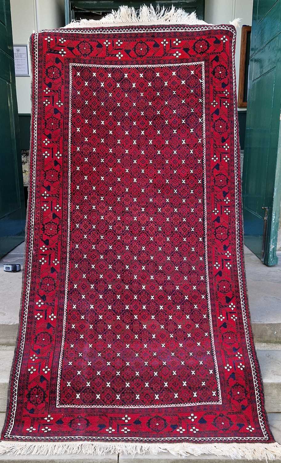 An Iranian madder ground rug, the rectangular field decorated with all over design of octagonal