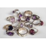 A collection of thirteen assorted white metal dress rings all set with amethyst coloured stones.