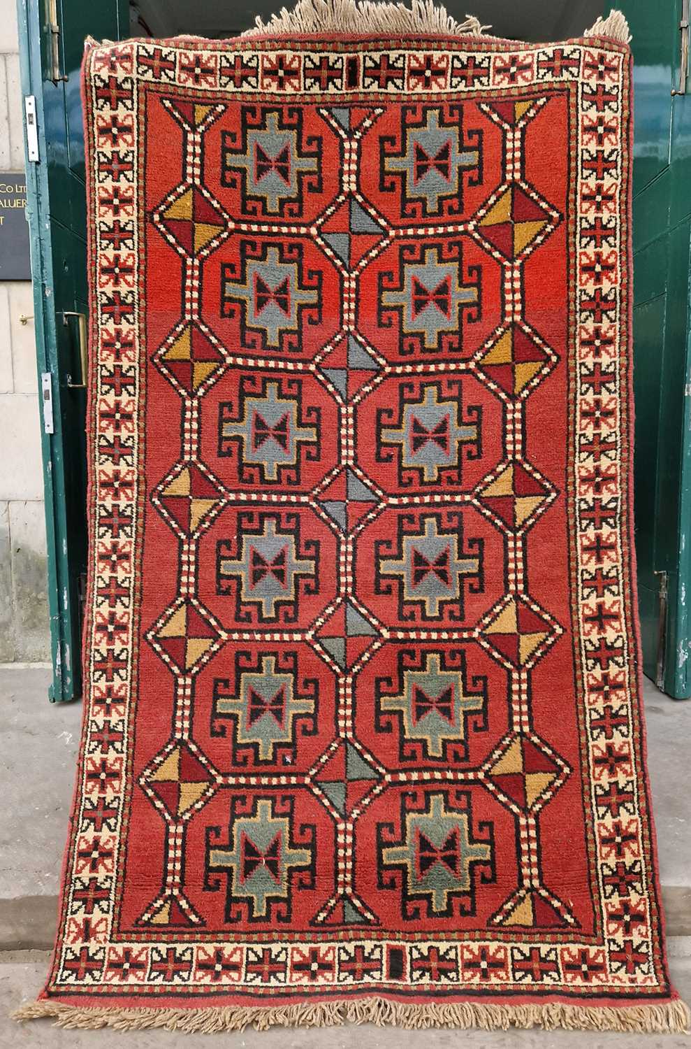 A Persian rug, Ghoochan, the rectangular madder field decorated with two rows of six octagonal
