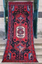 A Persian long rug, 20th century, the charcoal coloured ground centred with an ivory medallion and