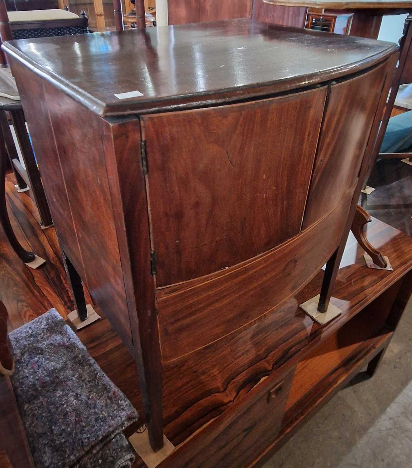 An anique mahogany and boxwood lined bowfront commode with two cupboard doors, 59cm wide.