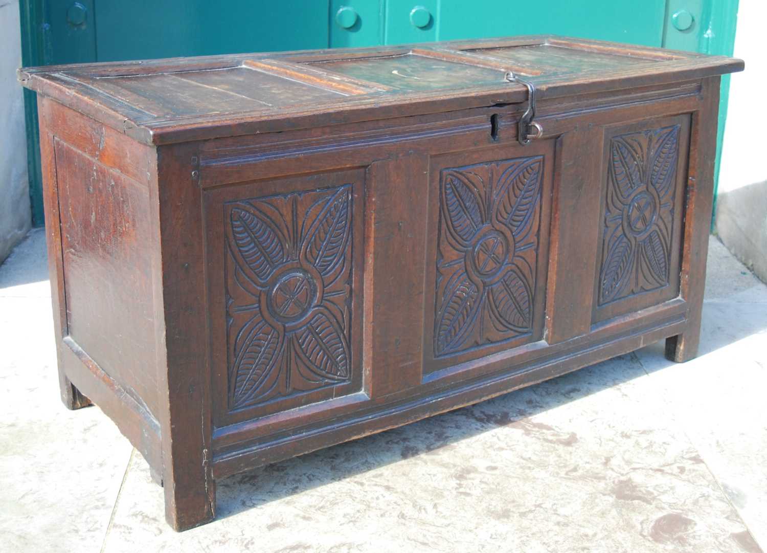 A George III oak coffer, the triple panel hinged cover over a triple panel front carved with three