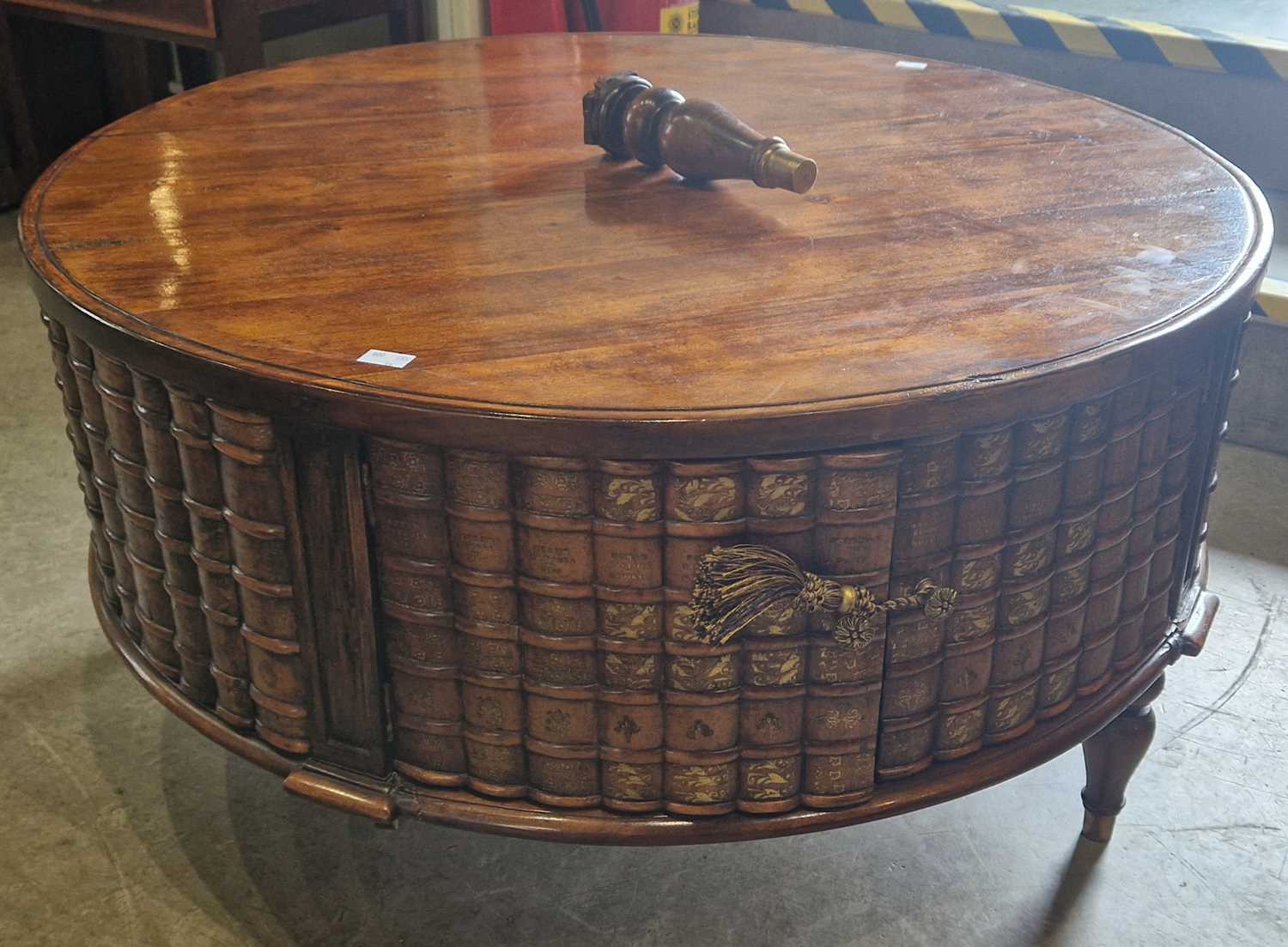 A modern mahogany and faux book circular shaped coffee table, the frieze with two pairs of