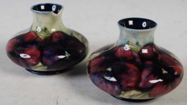 A pair of Moorcroft pottery vases decorated with pansies and foliage on a green/ blue ground,