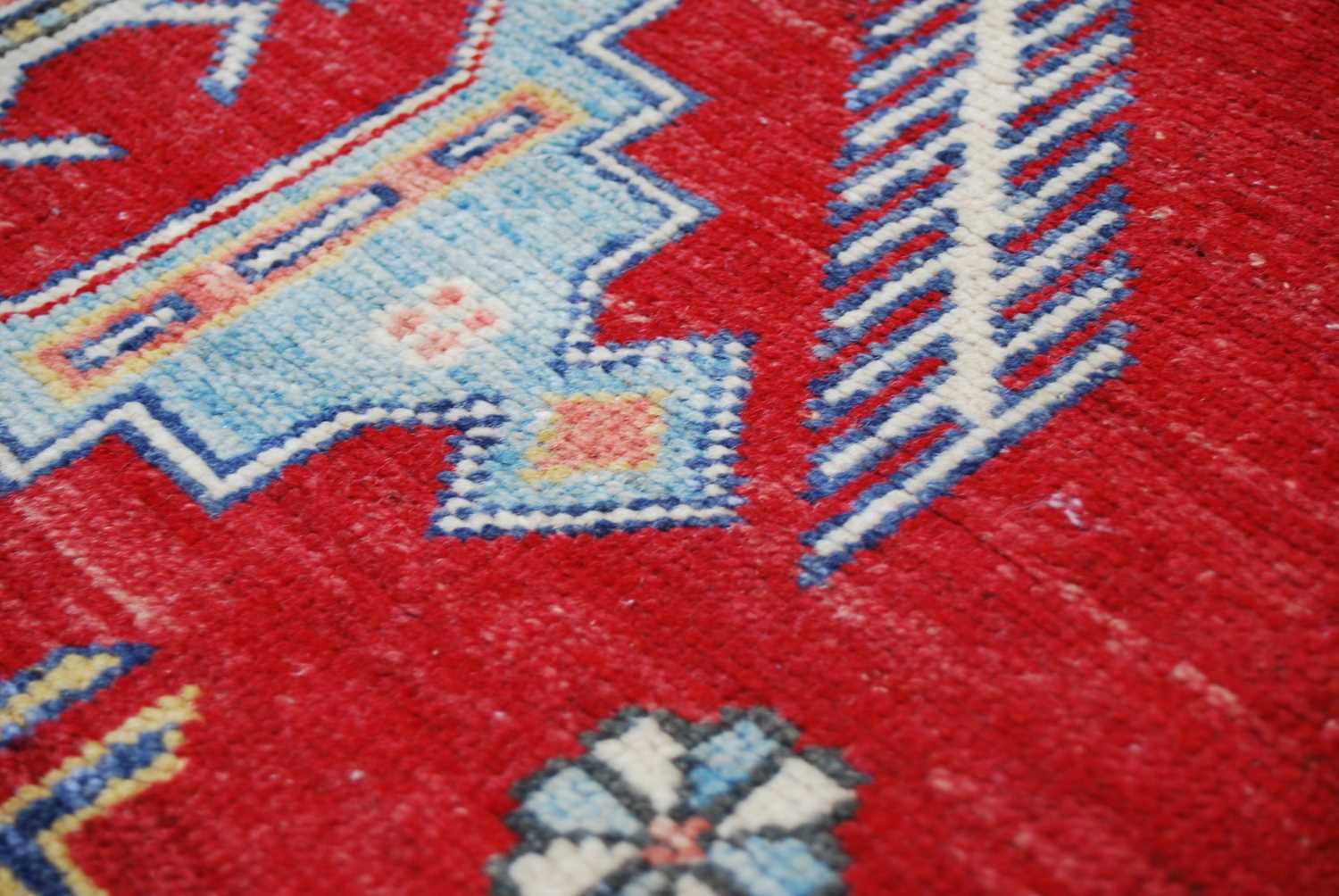 An Afghan Kazak rug, 20th century, the rectangular madder ground centred with a large blue ground - Image 5 of 5