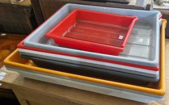 A collection of nine assorted vintage coloured plastic photography developing trays, the largest