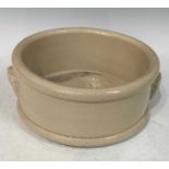 An early 20th century stoneware circular bowl with shell-shaped handles and three short bun feet,