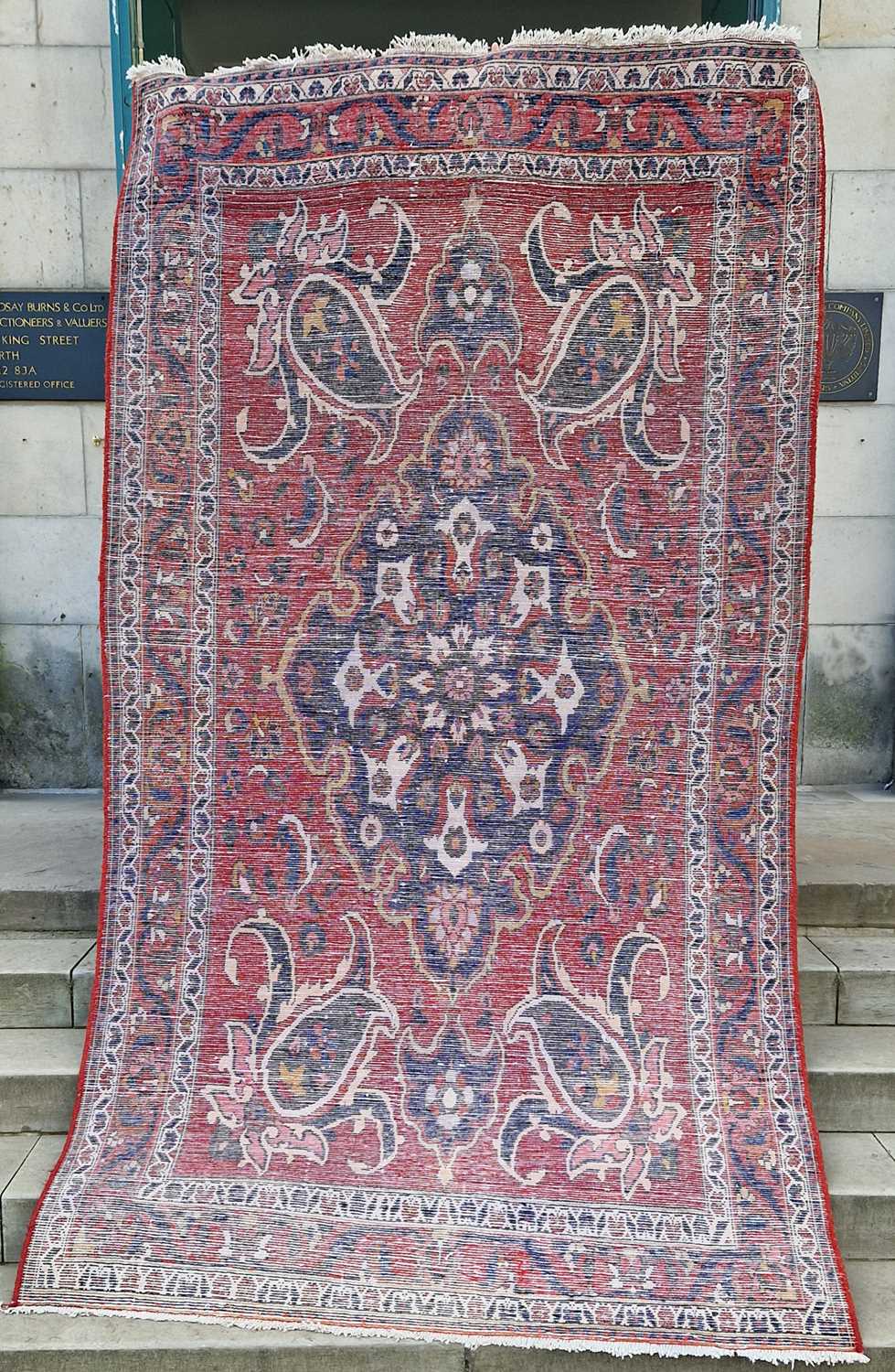 A Persian rug, 20th century, the rectangular madder ground centered with a blue ground oval - Image 2 of 5