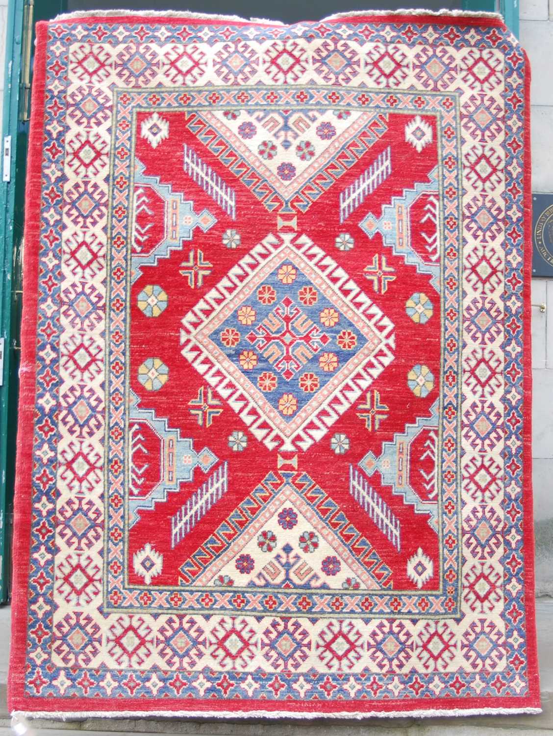 An Afghan Kazak rug, 20th century, the rectangular madder ground centred with a large blue ground