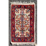 A small Persian mat, the ivory ground decorated with stylised flower motifs in a madder and blue