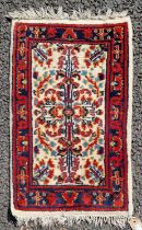 A small Persian mat, the ivory ground decorated with stylised flower motifs in a madder and blue