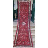 A Persian runner, 20th century, the madder ground centred with an ivory coloured floral medallion