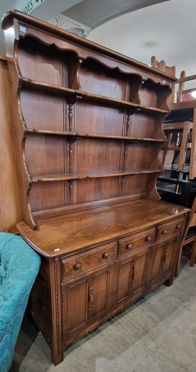 An ercol darkwood dresser, the upright back with three open shelves on a base fitted with three