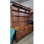 An ercol darkwood dresser, the upright back with three open shelves on a base fitted with three