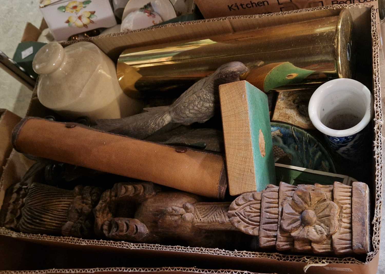 A box of assorted mixed wares to include a brass shell casing, carved wooden figure, spelter