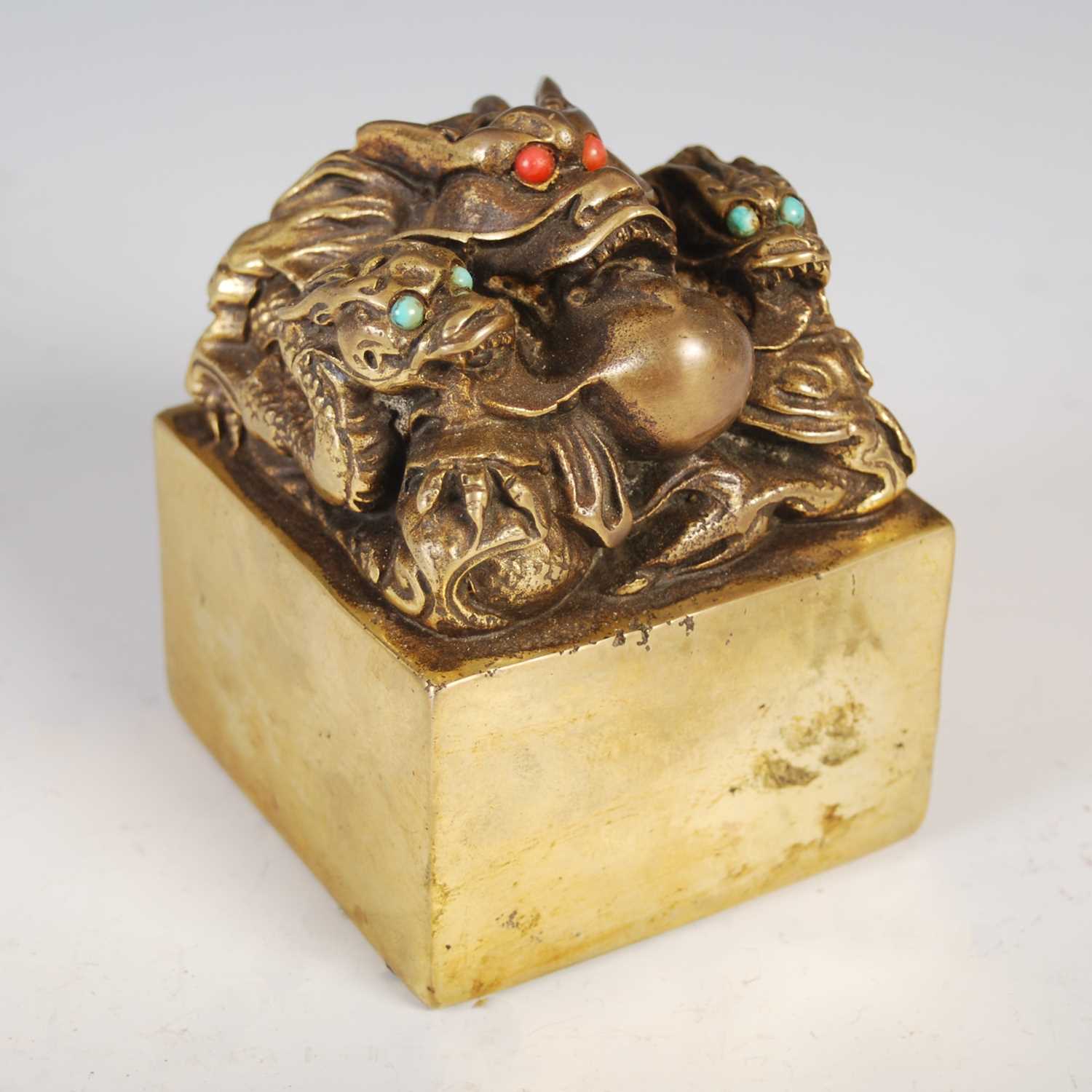 A Chinese gilt metal seal, early 20th century, modelled with three dragons and a flaming pearl,