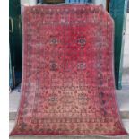 A Persian rug, 20th century, the madder ground decorated with six rectangular shaped medallions