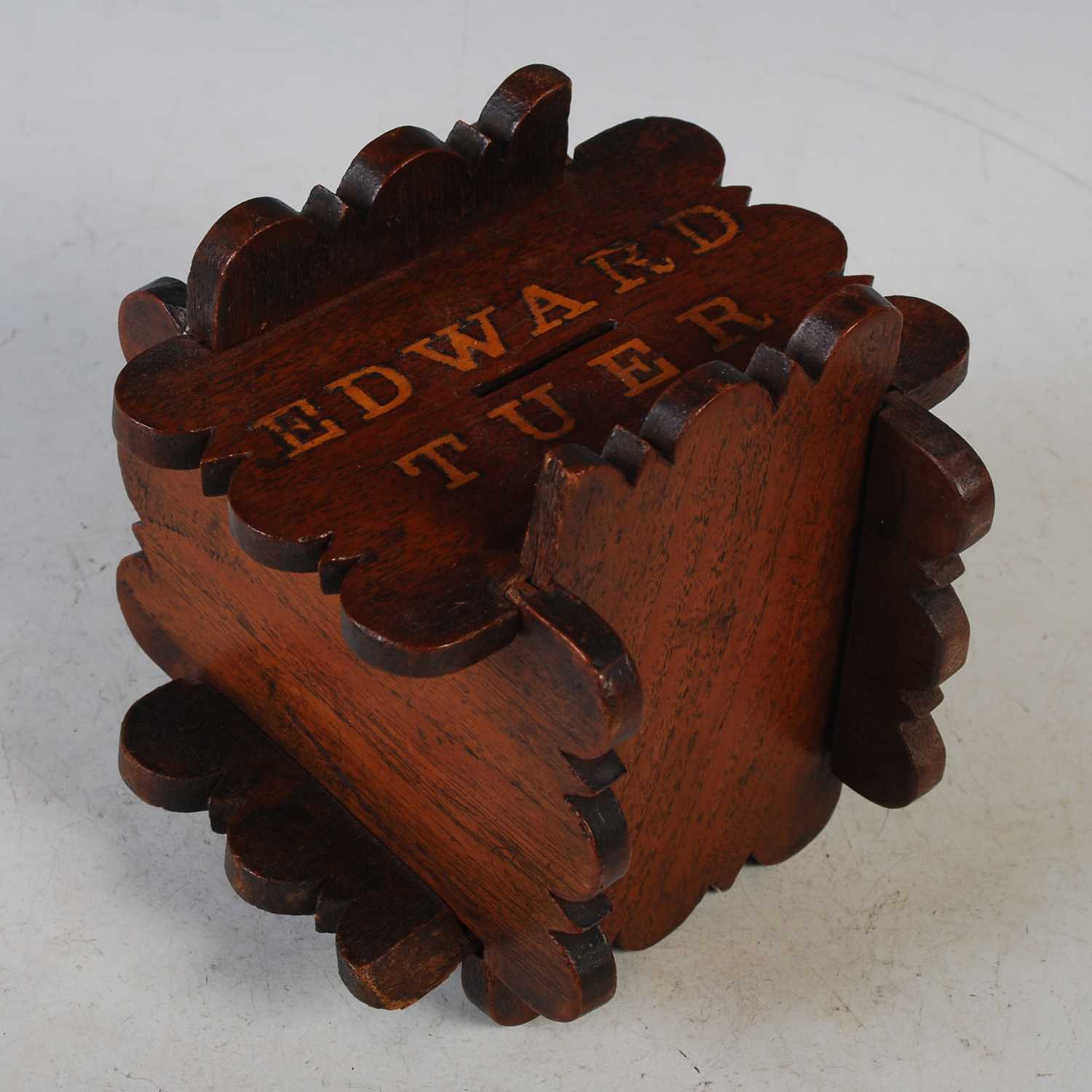 A mahogany puzzle money bank inscribed ‘Edward Tuer’, 14cm high x 14cm wide.