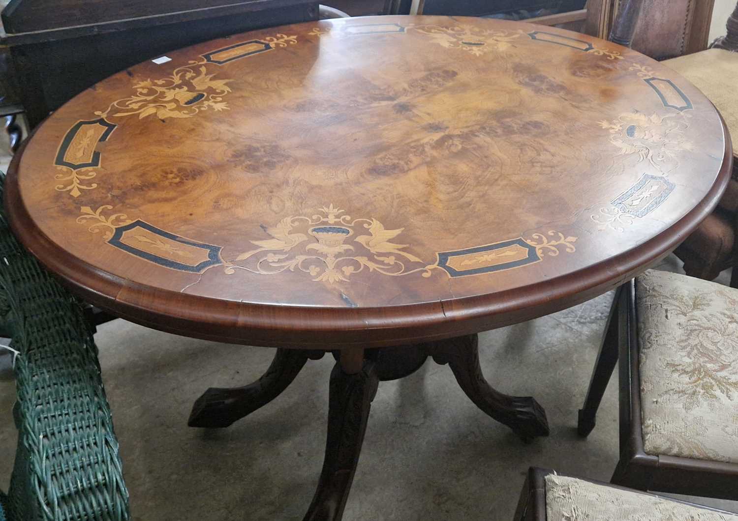 A walnut and marquetry inlaid oval snap-top table (lacking pins), 118cm wide.