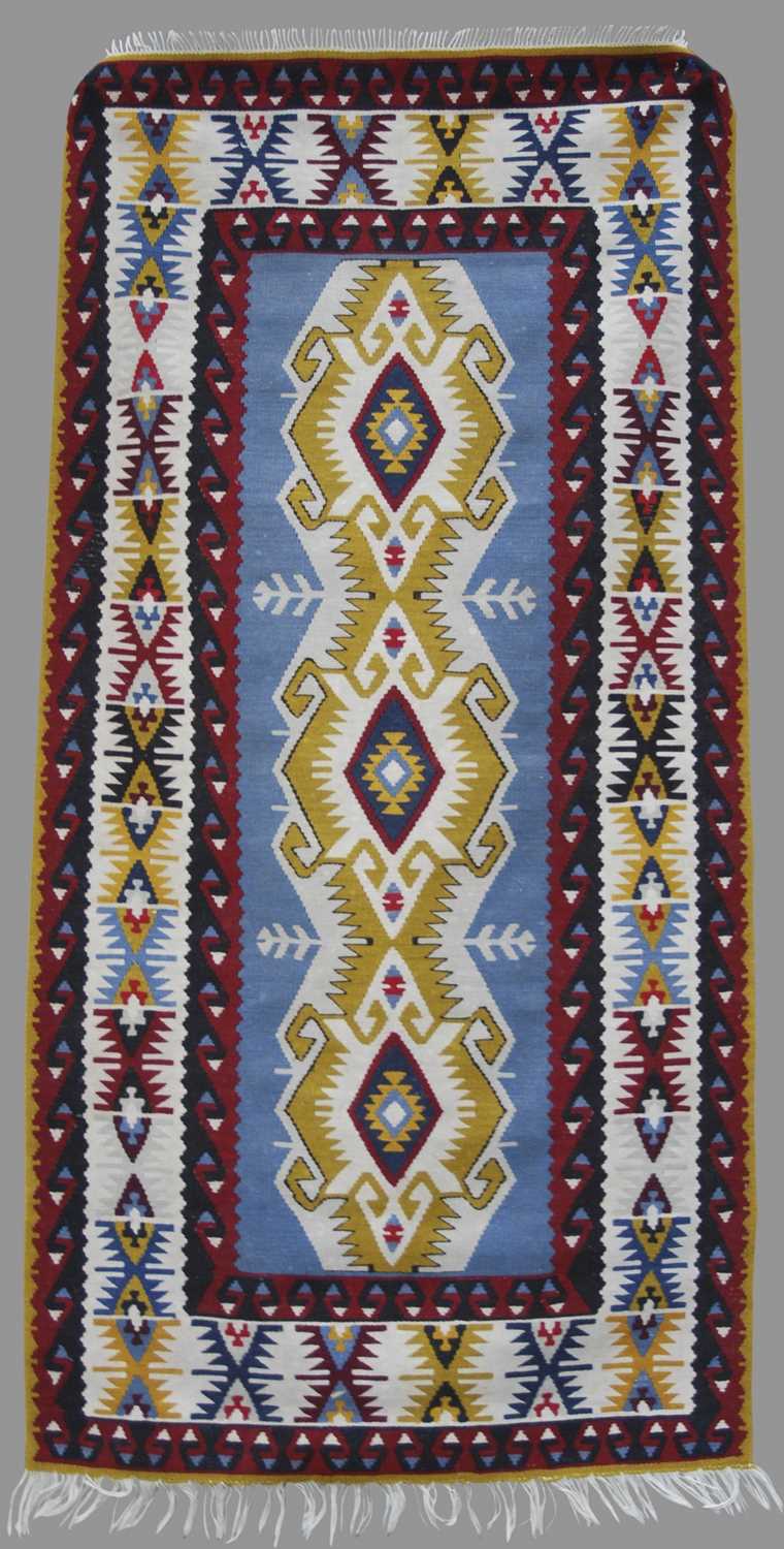 A Kelim rug, 20th century, the rectangular blue ground centred with a row of three lozenge shaped