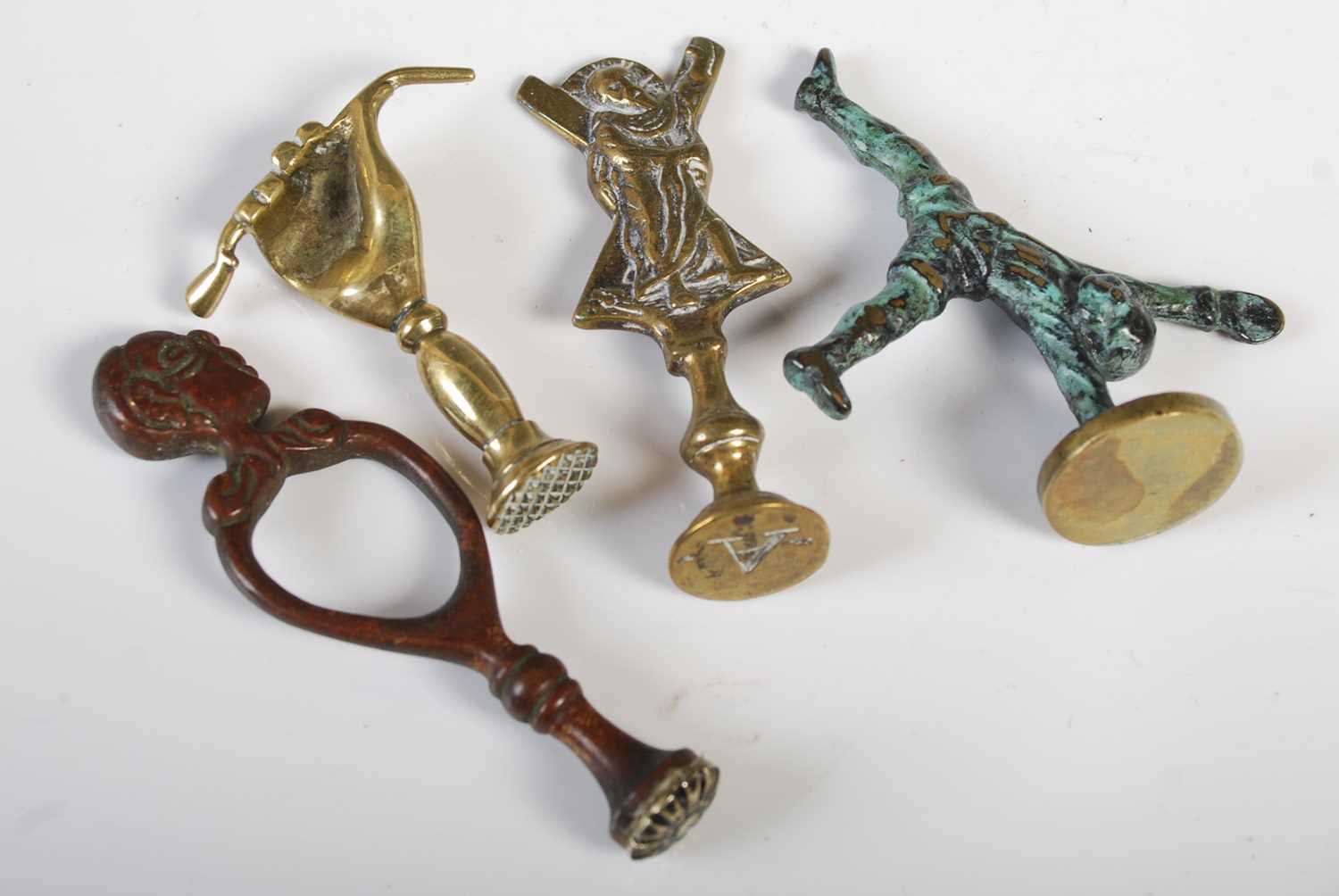 Four assorted antique brass pipe tampers, to include one in the form of a hand holding a pipe.