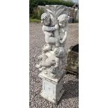 Stone pedestal adorned with cherubs and dolphins on stone base - Approx height: 138cm