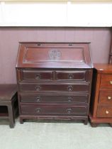 An oriental style stained wood bureau, the fall over two short over three long drawers on bracket