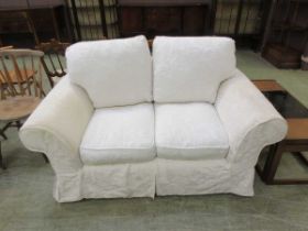 A 20th century two seater settee upholstered in a white floral fabric