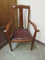 An early 20th century oak framed open arm chair with drop in seat