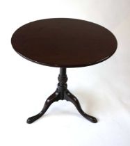 A George III mahogany one piece top occasional table, with tilt action, on a turned column with