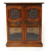 A late 19th century oak table top smokers cabinet, the doors with patinated copper roundels embossed