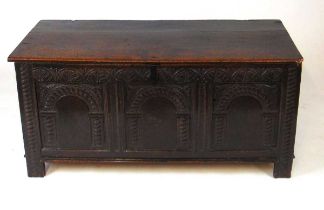 A late 17th/early 18th century oak coffer, the two plank top over an arcaded foliate band in turn