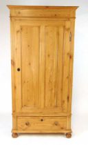 An early 20th century pine single wardrobe, with applied moulded pediment above a two panel door