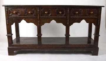 A 17th century style oak dresser base, the top consisting of a large single plank with later