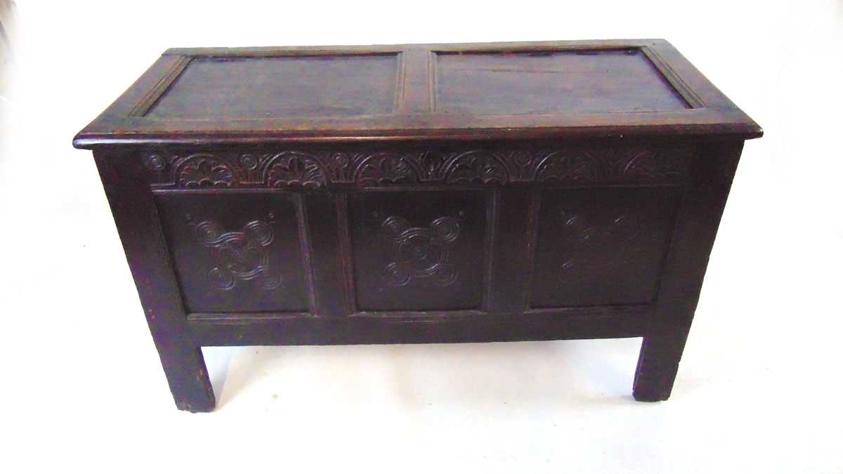 An early 18th century carved oak coffer, with foliate arcaded frieze above three carved panels, on
