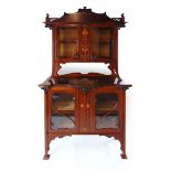 An Art Nouveau mahogany and inlaid display cabinet, the shaped glazed doors flanked by sinuous,