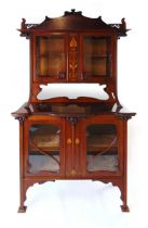 An Art Nouveau mahogany and inlaid display cabinet, the shaped glazed doors flanked by sinuous,