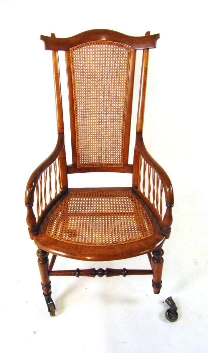 A Victorian beech bergere armchair, with shaped top rail, on brass castors, 109cm high