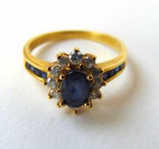 An 18ct gold sapphire and diamond cluster ring with channel set shoulders. Size N 1/2. Approx.