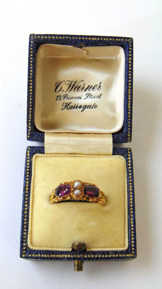 A mid Victorian 15ct gold, almandine garnet and pearl ring with openwork scrolling shoulders and