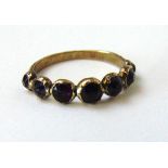 A 19th century yellow metal ring set with seven old cut amethysts. Size N. Approx. weight 1.9g A/F