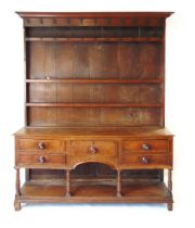 An 18th century oak dresser, with moulded pediment over three shelves and iron hooks, the base
