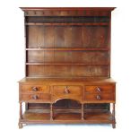 An 18th century oak dresser, with moulded pediment over three shelves and iron hooks, the base