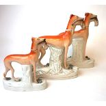 Three 19th century Staffordshire greyhounds, each modelled with a dead hare in their jaws,