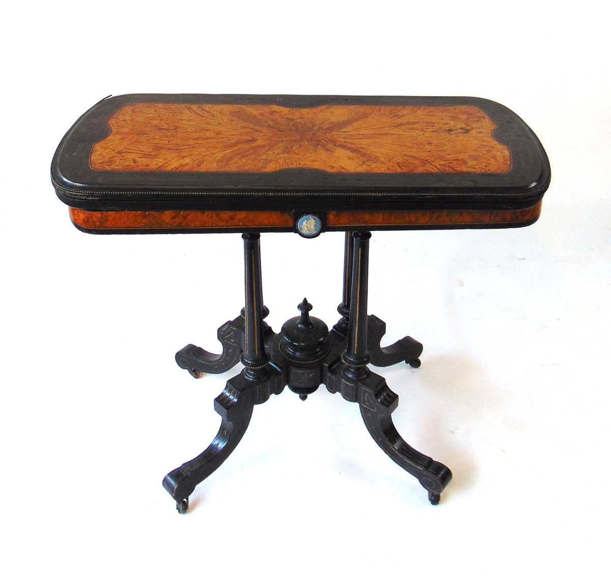 An Aesthetic period ebony and amboyna veneered card table, the top with shallow carved bellflower